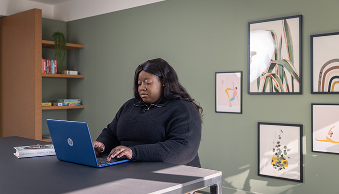 First time buyer searching on her laptop in a Pocket Living development's communal space.